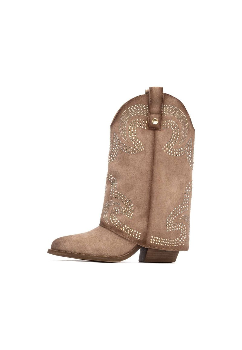 Bota vaquera de ante marrón con punta afilada, patrón decorativo de espirales en tachuelas metálicas, tacón corto y una lengüeta en la parte trasera.