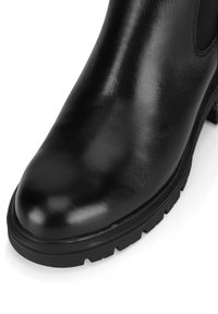 Melnas ādas potītes zābaki ar gludu apdari, apaļu purngalu, biezu gumijas zoli un elastīgām sānu paneļiem vieglai uzvilkšanai.