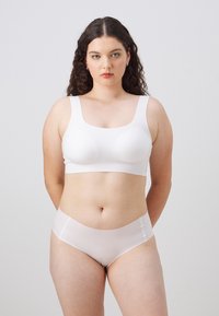 Hvit sømløs bh med formede kopper og brede stropper, kombinert med lys rosa sømløse truser. Glatt, elastisk stoff med en matt finish.