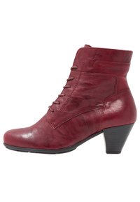 Botas de tobillo de cuero rojo con punta cerrada, diseño de cordones y tacón de altura media, que presentan una textura suave y un ligero brillo.