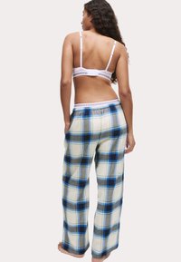 Geruite katoenen pyjamabroek in blauw, grijs en crèmekleur, met een lichte pasvorm en een elastische tailleband. De achterkant heeft een eenvoudig design.