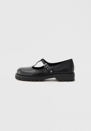 Scarpe Mary Jane in pelle nera con punta rotonda, design a T, due fibbie regolabili e suola chunky texturizzata.