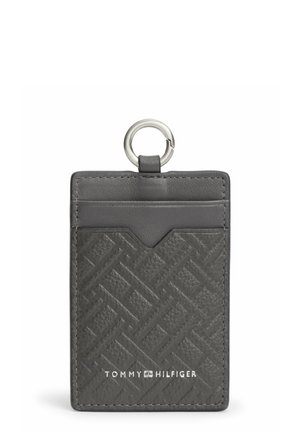 Czarny teksturowany skórzany uchwyt na karty z metalowym pierścieniem i przednią kieszonką, z białym logo Tommy Hilfiger na dole na środku.