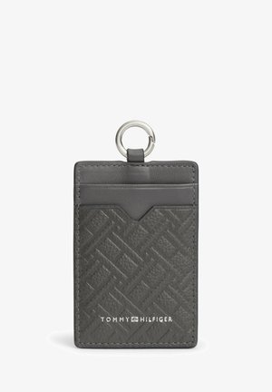 Portacarte in pelle nera texture con anello metallico e tasca frontale, con logo Tommy Hilfiger bianco al centro in basso.