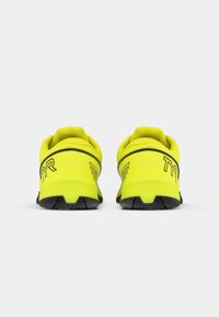 Gele sportschoenen met een zwarte zool en accenten. Zacht textiel bovenwerk met een gewatteerde kraag en een helder logo-detail op de hiel.