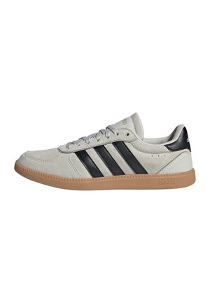 Lichtgrijze suède Adidas sneaker met zwarte strepen, gum rubberen zool, vetersluiting en zwarte hieltab met logo.