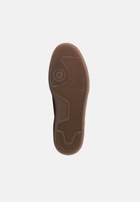 Καφέ λαστιχένια σόλα παπουτσιού με σχεδιασμένη λαβή. Διαθέτει κυκλικό πέλμα στο κέντρο, ανάγλυφη λεπτομέρεια και λεία άκρη γύρω από το περίγραμμα.