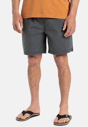Grijze katoenen shorts met een ontspannen pasvorm, zijzakken en een eenvoudige zoom. Gecombineerd met zwarte slippers met een beige zool.