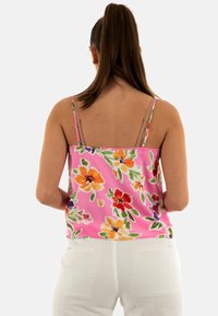 Camiseta de satén floral rosa con tirantes finos, que presenta un vibrante patrón de flores naranjas, rojas y moradas, y un corte holgado.