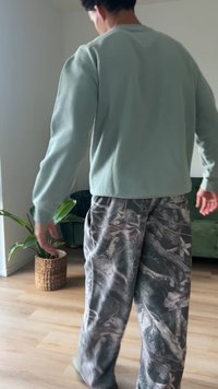 Helles grünes Sweatshirt mit langen Ärmeln, kombiniert mit grauen Schlafanzughosen, die ein dezentes, naturinspiriertes Muster aufweisen.
