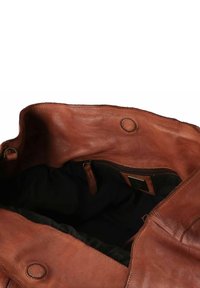 Bruine leren handtas met een zachte textuur, voorzien van een zwarte voering, een ritsvak en ronde hardware accenten aan de binnenkant.