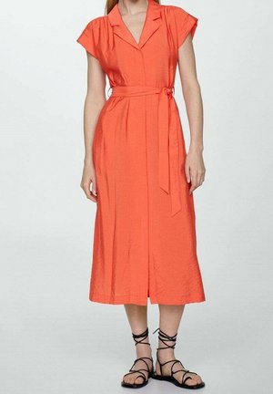 Oranje midi-jurk met korte mouwen, wikkelontwerp en een strikceintuur in de taille. Gladde textuur, valt net onder de knie. Zwarte sandalen met bandjes.