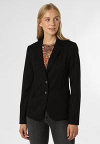 Czarny żakiet o dopasowanym kroju, z zapięciem na jeden guzik i dwiema przednimi kieszeniami. Noszony na tle bluzki w kwiatowy wzór, charakteryzuje się gładką teksturą.