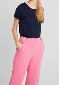 Camiseta navy con mangas cortas enrolladas combinada con pantalones rosa de tiro alto que cuentan con bolsillos laterales y una textura suave.