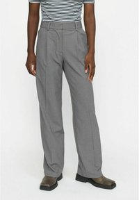 Grau, hoch taillierte Hose mit geradem Bein, subtiler Textur, zwei vorderen Falten und Gürtelschlaufen, kombiniert mit dunklen, klobigen Schuhen.