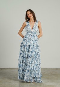 Vestido largo y con volantes en azul claro con estampados florales. Presenta un escote en V y una cintura ajustada, confeccionado en una tela ligera y fluida.