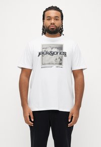 Λευκό βαμβακερό t-shirt με κοντά μανίκια, που φέρει γραφικό με μαύρα και γκρι βουνά και τη φράση «Jack & Jones» σε έντονα γράμματα.