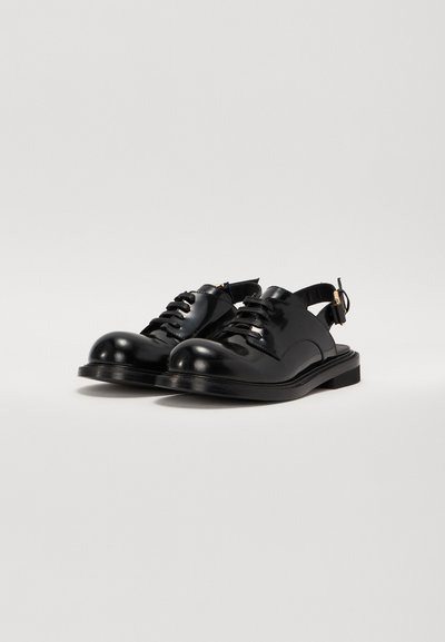 Black patent leather shoes with a rounded toe, lace-up front, and an ankle strap. Flat sole with subtle stitching details.