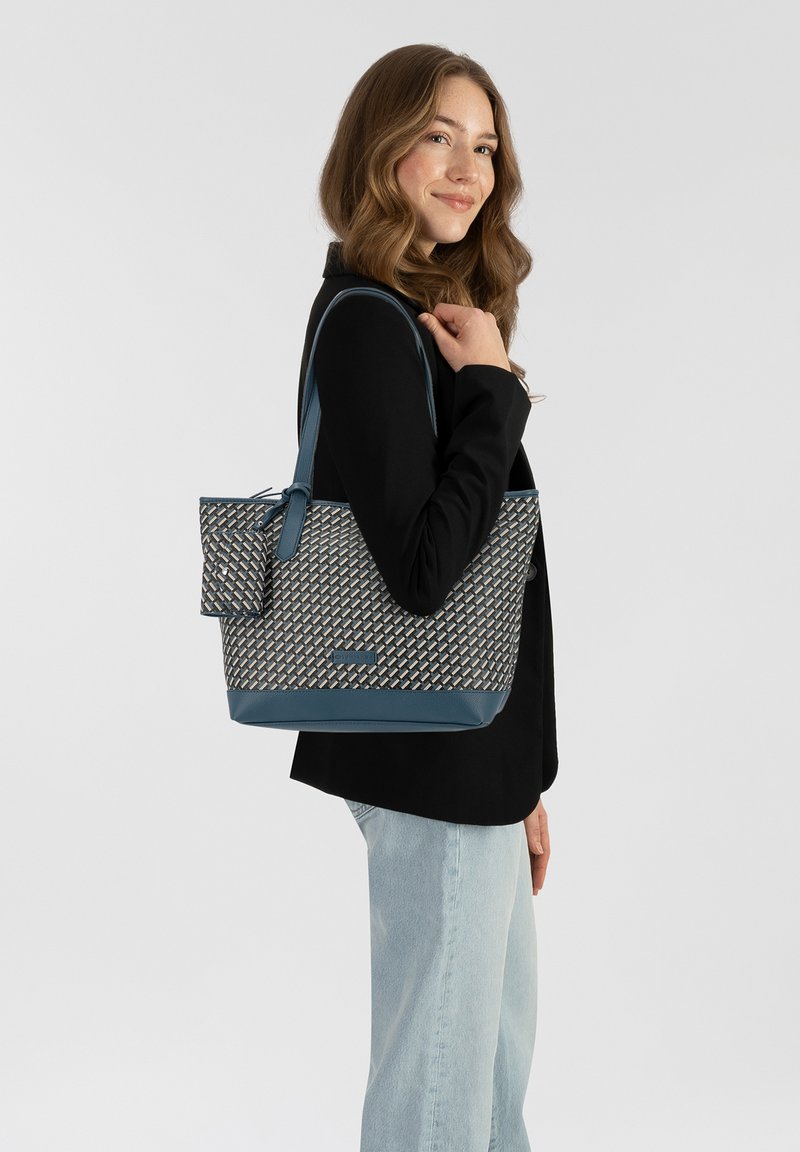 Sac fourre-tout avec un corps en textile à motif beige et marine, un fond lisse marine et des accents. Comprend une petite pochette détachable.