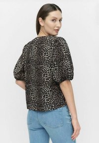 Leopardskindsprint top i let stof, med pufærmer og en buet kant. De dominerende farver er sort, brun og beige.