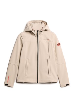 Veste softshell beige avec capuche, fermeture éclair, poches latérales et accents de logo. Présente un cordon de serrage contrastant et des écussons de marque.