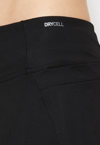 Leggings deportivos negros con cintura alta, textura suave y detalles cosidos, con un logotipo "DRYCELL" en la parte superior de la espalda.