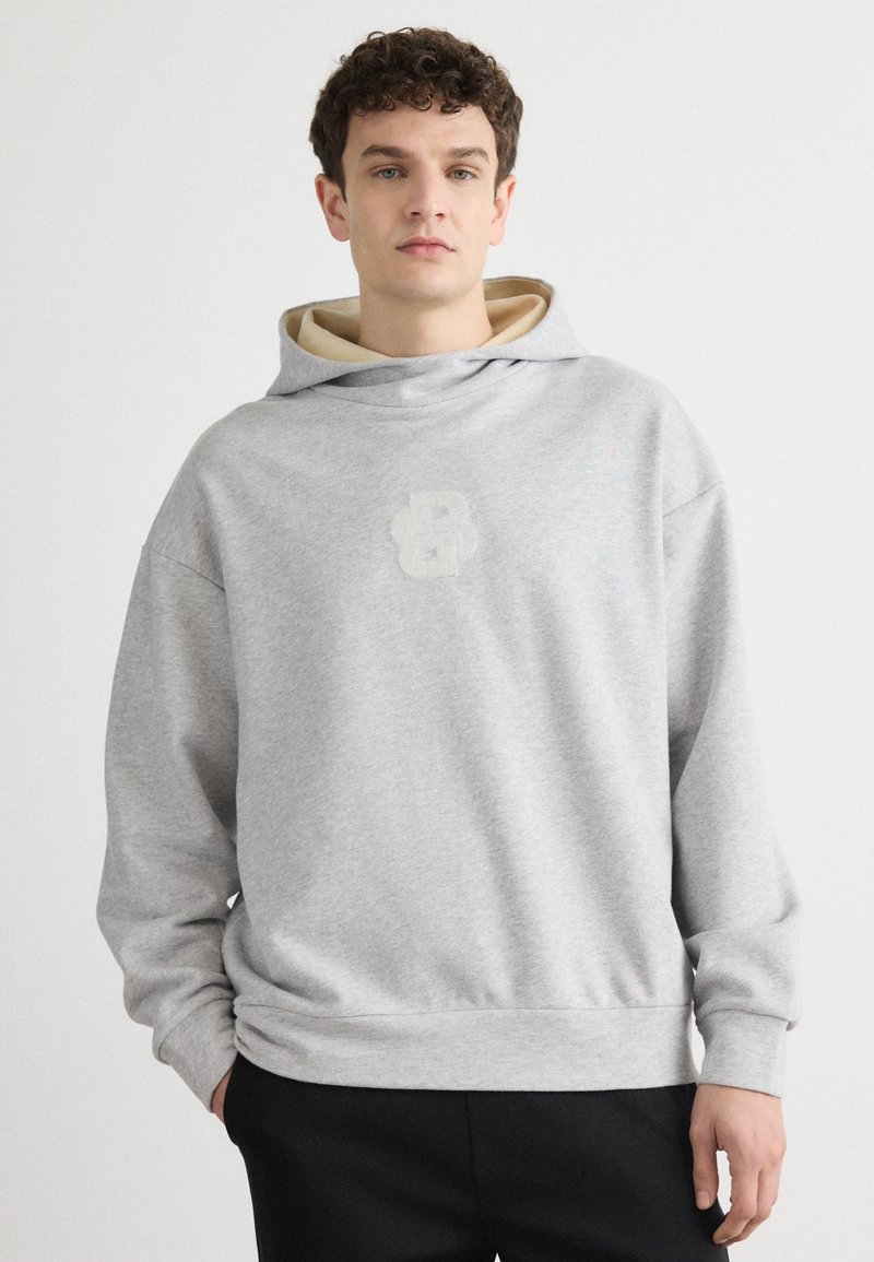 Sweatshirt cinza com uma textura grande e suave e um interior creme. Apresenta um logotipo subtil em cinza claro na frente e um corte descontraído.