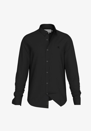Camicia nera a maniche lunghe con colletto button-down, vestibilità slim, caratterizzata da cuciture sottili e un piccolo logo sul petto. Tessuto di consistenza liscia.