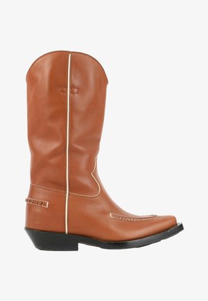 Botte de cowboy en cuir fauve avec talon noir, bout pointu, coutures blanches et hauteur mi-mollet sur fond blanc.