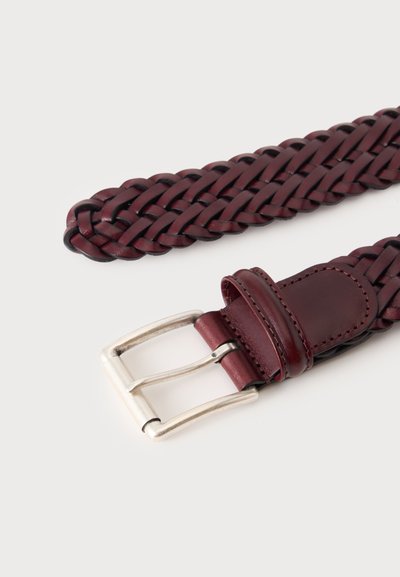 Ceinture en cuir rouge foncé tressé avec boucle rectangulaire argentée et passant en cuir cousu sur un fond clair.
