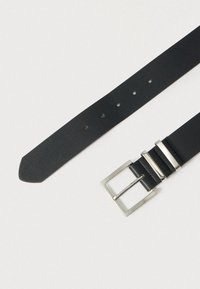 Μαύρη δερμάτινη ζώνη με ορθογώνιο ασημένιο μεταλλικό αγκράφα, με πολλές τρύπες ρύθμισης και ματ, υφασμένη επιφάνεια.
