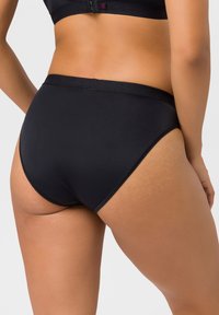 Schwarze Hipster-Briefs bestehen aus einem glatten, dehnbaren Stoff mit einem breiten Bund. Das Design ist schlicht und figurbetont, ohne sichtbare Muster.