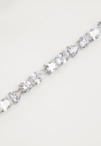 Pulseira prateada com uma série de grandes pedras transparentes facetadas em várias formas, incluindo redonda, pêra e quadrada, com um acabamento polido.