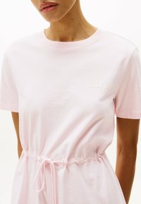 Roze katoenen T-shirt met korte mouwen, voorzien van een elastische taille en een trekkoord. Geborduurd logo in een lichtere tint roze.