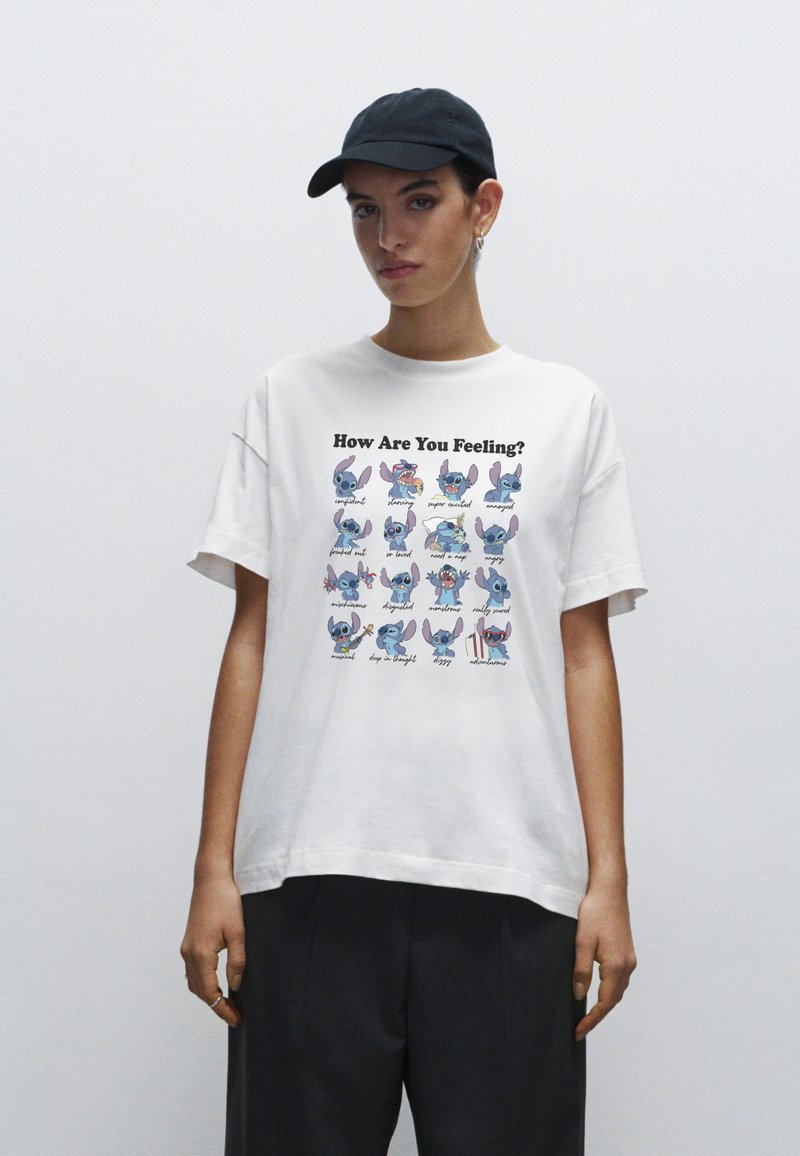White cotton t-shirt featuring colorful illustrated characters expressing various emotions, with text "How Are You Feeling?" printed above.