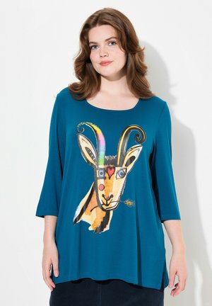 Teal oversized shirt met een ronde halslijn en driekwart mouwen, voorzien van een kleurrijke geit grafisch ontwerp op de voorkant.