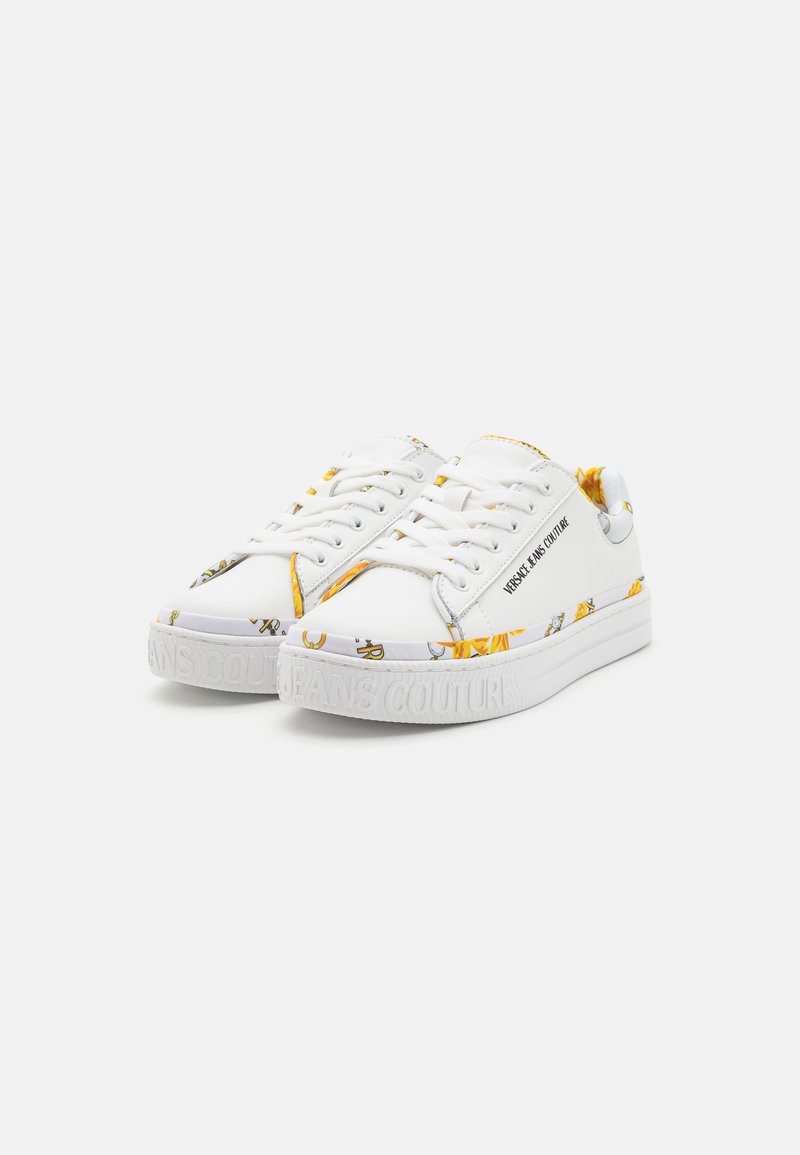 Zapatillas blancas con parte superior texturizada, que presentan acentos de patrón amarillo y una suela blanca gruesa con la inscripción "JEANS COUTURE".