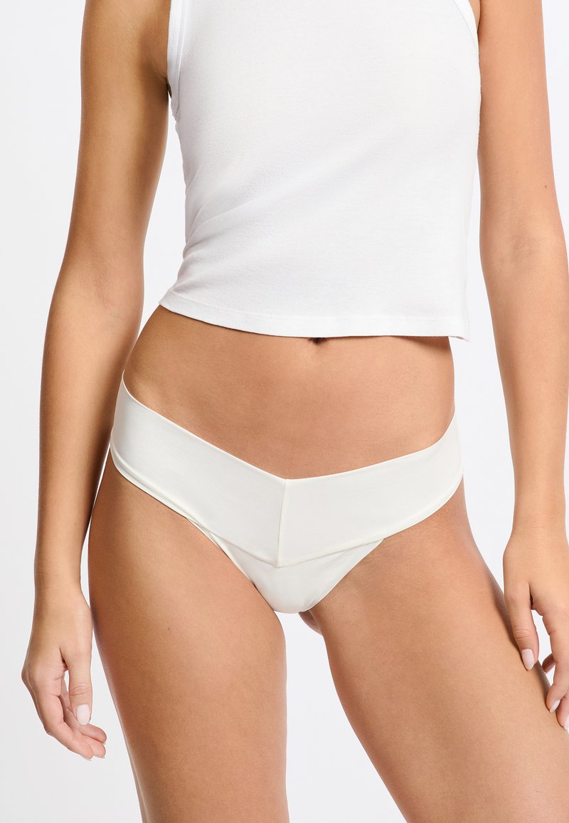 Parte inferior de bikini de satén blanco con cinturilla ancha y diseño frontal en forma de V, con textura suave y estilo minimalista.
