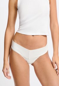 White satin bikini bottom featuring a wide waistband and v-shaped front design, with smooth texture and minimalistic style.