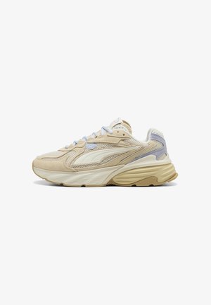 Beige og hvid atletiksneaker med mesh og ruskind detaljer, tyk polstret sål og lyse lilla accenter, sidevisning.
