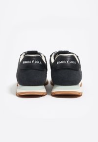 Zapatillas de ante negro y malla con un forro crema, que cuentan con una suela de goma y el logo "BIMBA Y LOLA" en el talón trasero.