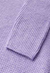 Pull en maille lavande avec un motif texturé et des poignets côtelés. Le tissu semble doux et chaud, mettant en avant un design confortable.