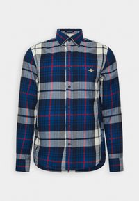 Camisa de franela a cuadros en azul marino, gris y rojo, con mangas largas, cuello abotonado y bordado del logo en el pecho.
