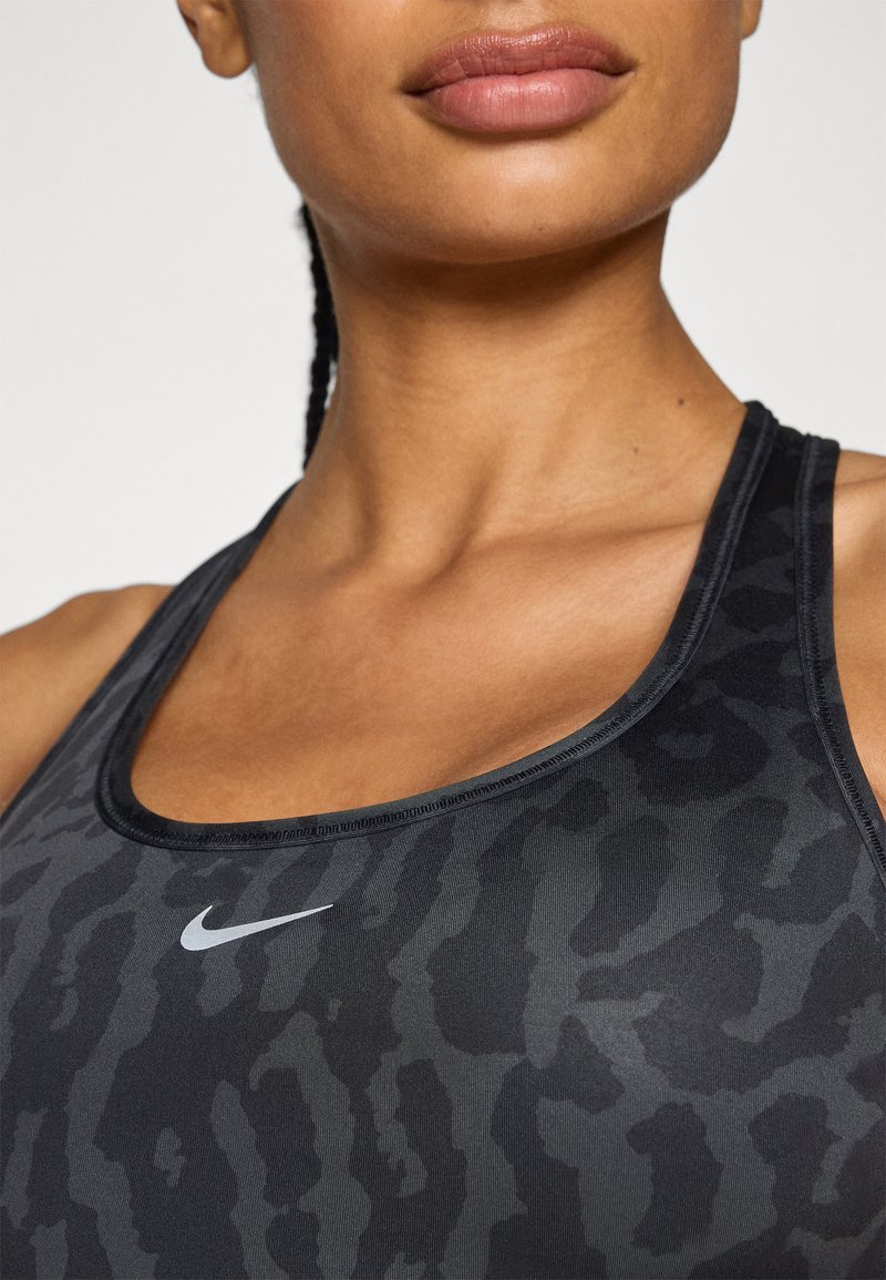 Soutien-gorge de sport noir avec un motif subtil d'imprimé animal, fabriqué en matière extensible, avec un décolleté arrondi et un petit logo Nike blanc.
