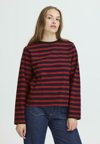 Red and navy striped long-sleeve shirt with a round neckline, made of soft cotton material. The fit is relaxed and casual.