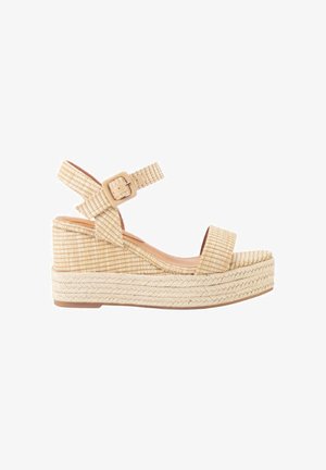 Sandalia de cuña beige tejida con correa en el tobillo, cierre de hebilla y suela con plataforma trenzada diseñada para uso casual.