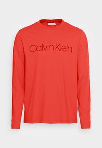 T-shirt rosso a maniche lunghe in cotone con collo girocollo e una stampa logo discreta di "Calvin Klein" in un colore a contrasto sul davanti.