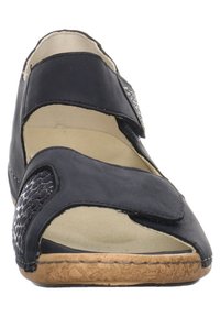 Sandale noire avec sangle réglable en Velcro, bout ouvert et panneau en imprimé animal texturé. Semelle en liège avec doublure intérieure beige clair.