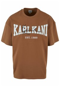 Brūna kokvilnas T-kreklu ar īsām piedurknēm. Ar baltu tekstu "KARL KANI" un "EST. 1989" izliektā izkārtojumā. Klasiska apaļa kakla dizains.