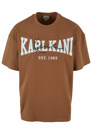 Maglietta in cotone marrone a maniche corte. Presenta il testo bianco "KARL KANI" e "EST. 1989" in una disposizione curvata. Design classico con scollo a girocollo.